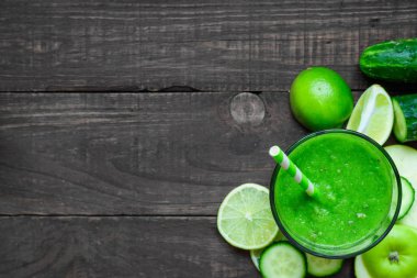 bir bardak ıspanak, elma, salatalık ve rustik ahşap masa üzerinde bir saman limonlu yeşil sağlıklı güler yüzlü