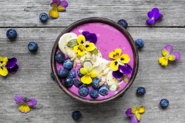 sağlıklı kahvaltı. güler yüzlü kase taze çilek, muz, chia tohum ve çiçekler ile tepesinde.