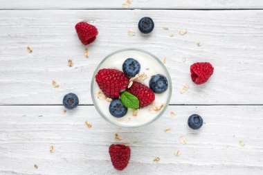 sağlıklı Yoğurtlu taze çilek, yulaf ve nane bir bardak beyaz tahta masada. sağlıklı kahvaltı