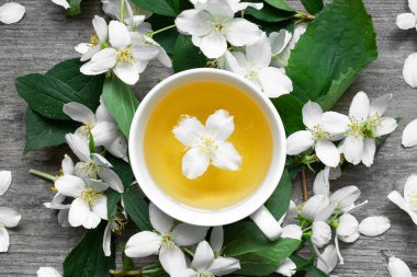 Ahşap arka planda yasemin çiçekli bir fincan çay.