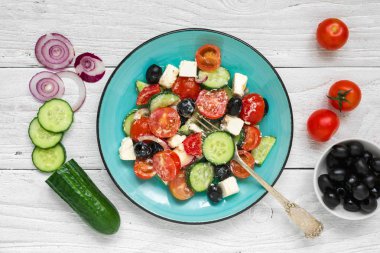 Taze sebze, beyaz peynir ve Siyah Zeytin beyaz tahta masada çatal ile bir plaka ile Yunan salatası