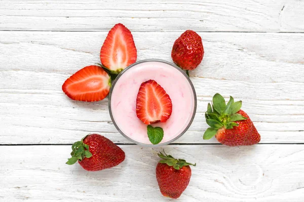 Yogurt de fresa en un vaso con bayas frescas sobre fondo de madera blanca. desayuno saludable — Foto de Stock