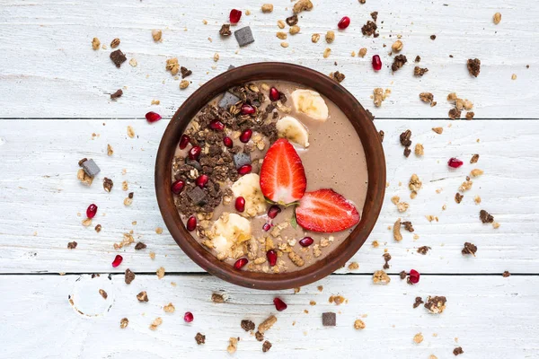 cocoa banana protein smoothie bowl with chocolate granola, strawberry and pomegranate seeds