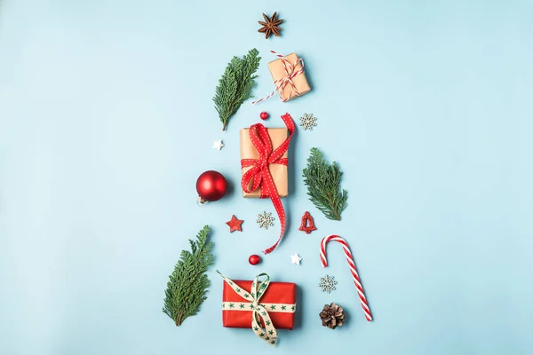 크리스마스 트리는 전나무 가지, 겨울 장식, 파란 배경에 놓인 사탕 과 선물 상자로 만들어 진다 — 스톡 사진