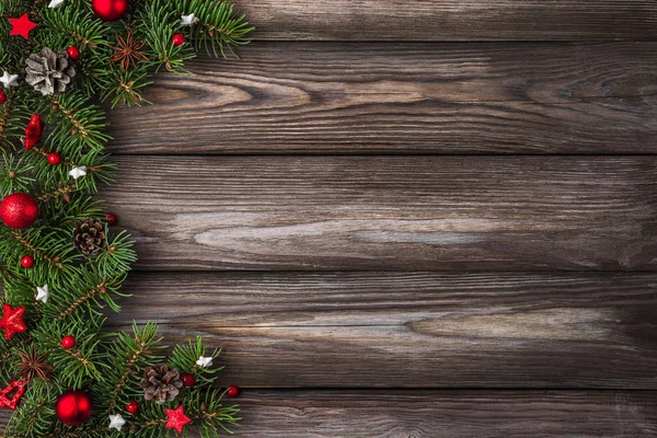 Wesołych Świąt i szczęśliwego Nowego Roku. Gałęzie jodły z czerwonymi dekoracjami wakacyjnymi na rustykalnym drewnianym stole — Zdjęcie stockowe