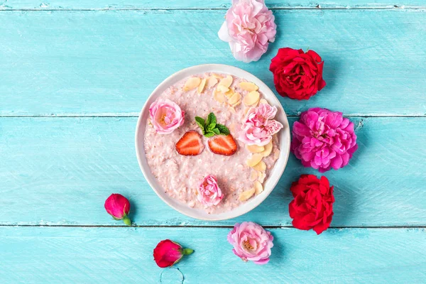 Aveia de morango durante a noite com bagas frescas e amêndoas em uma tigela com flores de rosa para o café da manhã romântico saudável — Fotografia de Stock