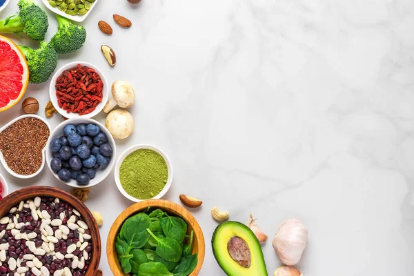 Comida vegana saludable selección de alimentos limpios: frutas, verduras, semillas, superalimentos, nueces, bayas sobre fondo de mármol blanco — Foto de Stock