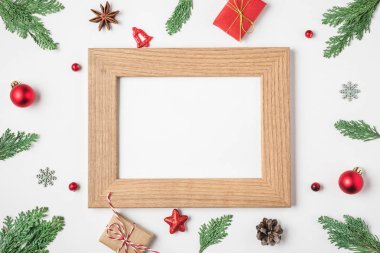 Köknar ağacı dallarından yapılmış çerçevede boş Noel kartı hediye kutuları, beyaz arka planda kırmızı tatil süslemeleri.