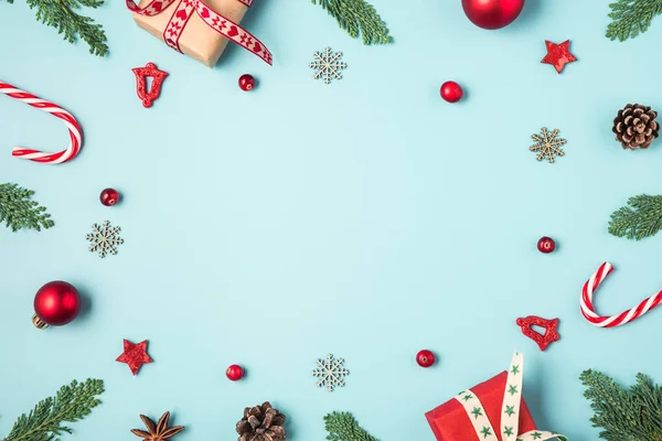 전나무 가지, 선물 상자, 사탕, 붉은 휴일 장식, 푸른 배경에 있는 솔방울로 만든 크리스마스 틀 — 스톡 사진