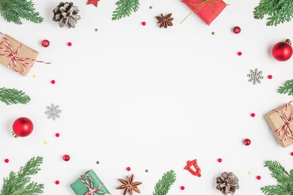 전나무 가지, 선물 상자, 붉은 휴일 장식, 하얀 배경에 있는 솔방울로 만든 크리스마스 틀 — 스톡 사진