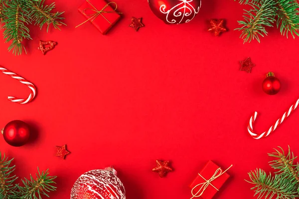 Marco de Navidad hecho de ramas de abeto, cajas de regalo, decoraciones de vacaciones rojas y dulces sobre fondo rojo —  Fotos de Stock