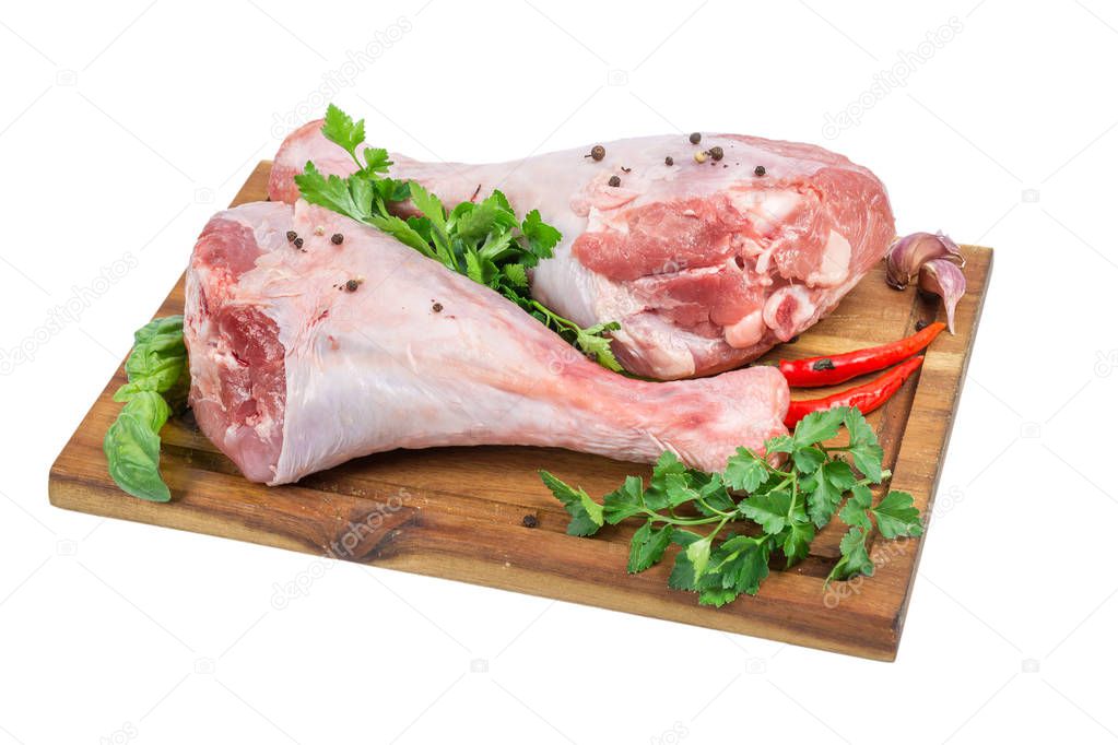 Raw turkey drumsticks or legs on wooden cutting board with herbs and spices isolated on white background