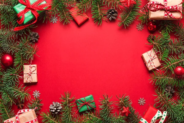 Karácsonyi lapos laikus keret fenyő ágak, ajándékdobozok, piros ünnep dekorációk piros háttér — Stock Fotó