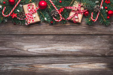 Noel kompozisyonu. Firavun ağacı dalları, hediye kutuları, süslemeler, şekerler, köy ahşap masasında çam kozalakları. en üstteki görünüm