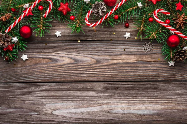 Vánoční a novoroční kompozice. jedle větve stromů, červená dovolená dekorace a cukroví na rustikálním dřevěném stole — Stock fotografie