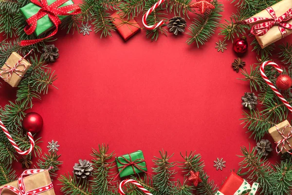 Navidad o Feliz Año Nuevo fondo rojo. Marco hecho de ramas de abeto, decoraciones navideñas y cajas de regalo —  Fotos de Stock