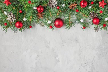 Köknar ağacı dalları ve çimento üzerine kırmızı bayram süslemelerinden oluşan Noel veya Mutlu Yıllar kompozisyonu