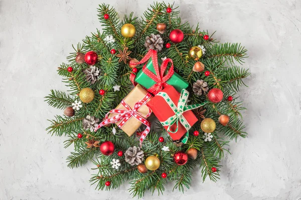크리스마스 기념 화환은 전나무로 만들어 졌고, 콘크리트 배경 위에 선물 상자가 놓인 휴일 장식으로 만들어 졌다. — 스톡 사진