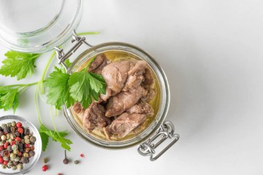 Kavanozda morina ciğeri, beyaz arka planda maydanoz ve biber. Doğal Omega 3 ve D vitamini kaynağı.