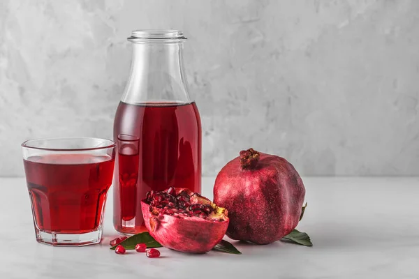 Zumo de granada en una botella con un vaso de jugo y frutas frescas de granada sobre una mesa de mármol. Bebida saludable — Foto de Stock