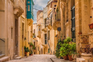 Birgu, Valletta, Malta 'da sarı binaları, güzel balkonları ve saksıları olan eski bir ortaçağ sokağı.