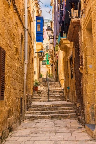 Antigua calle medieval estrecha con edificios amarillos con balcones de colores en la ciudad Singlea, La Valeta, Malta — Foto de Stock