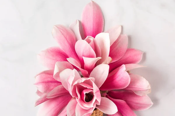 Tata letak kreatif dibuat dengan bunga magnolia merah muda pada latar belakang marmer putih. Berbaringlah. pemandangan atas. konsep musim semi — Stok Foto