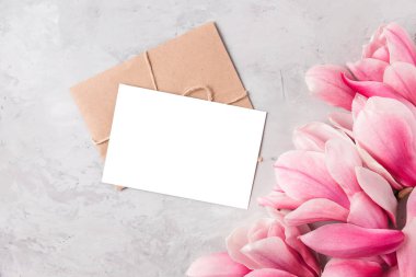 Beyaz arka planda pembe manolya çiçekleri olan boş bir tebrik kartı. Düğün davetiyesi. Model yap. Düz yatıyordu