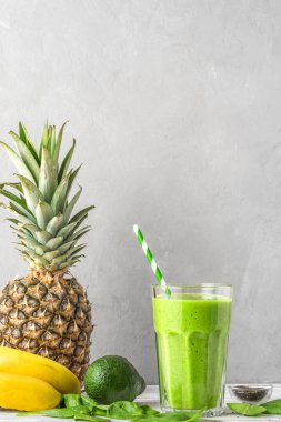 Çiğ vejetaryen sağlıklı içecek. Ispanak, ananas, avokado ve chia tohumlarından yapılmış pipetle dolu bir bardakta yeşil smoothie detoks. Kopyalama alanı ile dikey yönelim