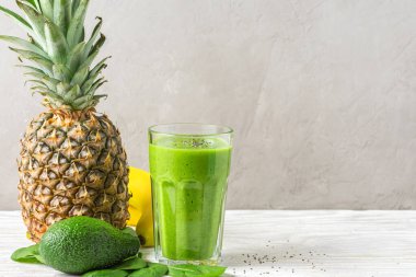 Ispanak, ananas, avokado, muz ve chia tohumlarından yapılmış bir bardaktaki sağlıklı yeşil smoothie. Çiğ vegan içeceği konsepti.