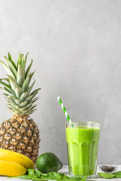 Çiğ vejetaryen sağlıklı içecek. Ispanak, ananas, avokado ve chia tohumlarından yapılmış pipetle dolu bir bardakta yeşil smoothie detoks. Kopyalama alanı ile dikey yönelim