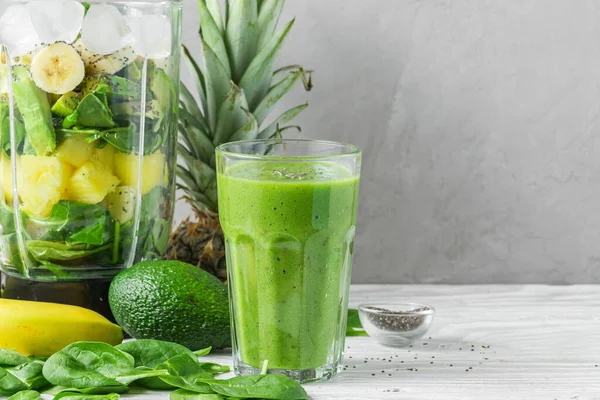 Blender for making smoothie and glass with green healthy smoothie detox made of spinach, pineapple, avocado, banana and chia seeds. Raw, vegan, vegetarian, cooking food concept