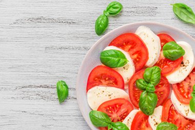 Olgun domatesli sağlıklı caprese salatası ve taze fesleğen yapraklı mozzarella peyniri. İtalyan yemeği. Kopyalama alanı olan üst görünüm