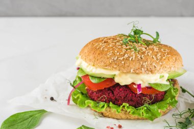 Avokado, salata, domates, lahanalı vejetaryen pancar burger ve beyaz mermer masada vegan mayonezi. Sağlıklı fast food