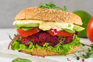 Avokado, salata, domates, lahanalı vejetaryen pancar burger ve beyaz mermer masada vegan mayonezi. Sağlıklı fast food