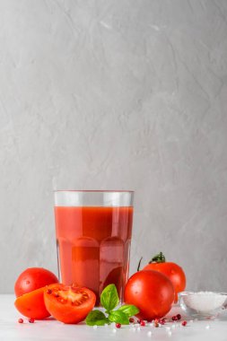 Taze domatesli domates suyu, fesleğen, tuz ve biberli beyaz mermer masa. düşey yönelim