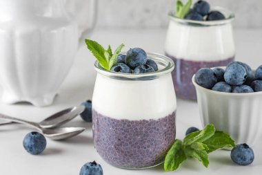 Sağlıklı kahvaltı hindistancevizli yoğurt ve taze böğürtlenli yaban mersinli puding ve bardakta nane şekeri. Vejetaryen yemeği. Kapat.