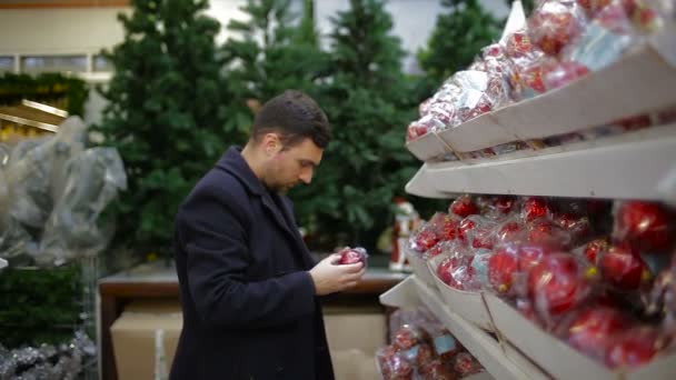 Man chooses Christmas decorations in a shop — Stock Video