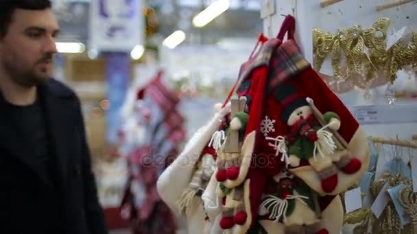 Homem escolhe brinquedos de Natal em um supermercado — Vídeo de Stock