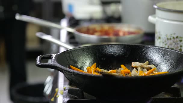 Chef freír verduras y carne en un wok en la cocina — Vídeo de stock