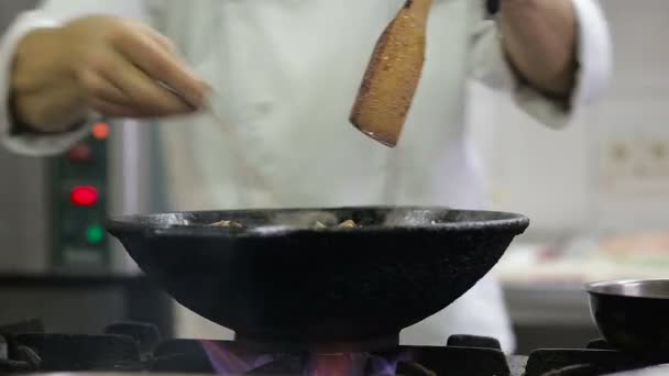 Шеф-повар жарит овощи и мясо в воке на кухне — стоковое видео