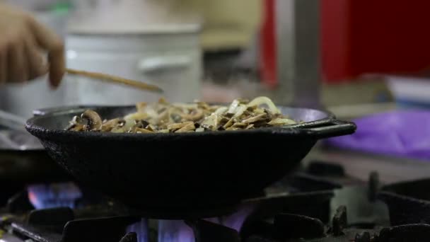 Paddestoelen zijn gebakken in een wok in de keuken — Stockvideo