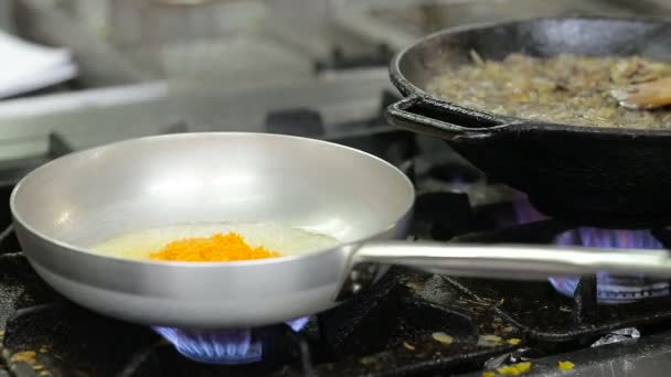 Нарезанный лук и морковь, обжаренные в растительном масле на сковороде — стоковое видео