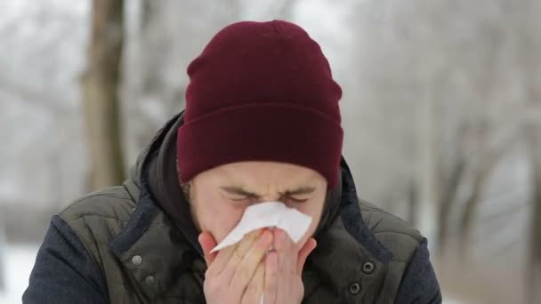 Hombre enfermo sonándose la nariz en el parque de invierno — Vídeo de stock