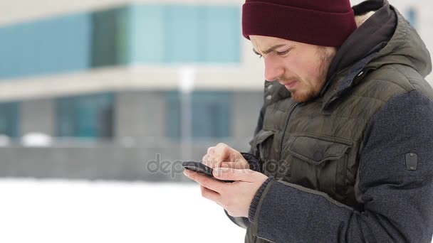 El hombre escribe sms invierno en la ciudad — Vídeo de stock