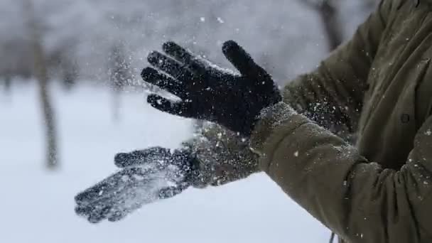 Man händerna med handskar skakar snö utomhus på vintern — Stockvideo