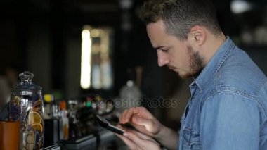 Bir adam barda otururken tablet kullanır