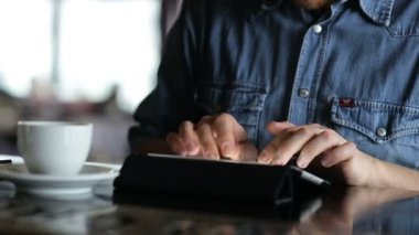 Genç adam barda otururken bir tablete yazma