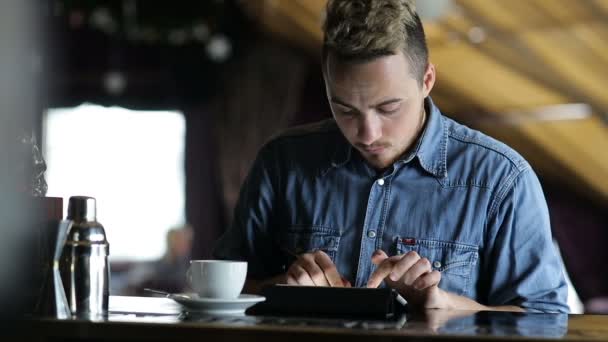 年轻人坐在酒吧在平板电脑上打字 — 图库视频影像