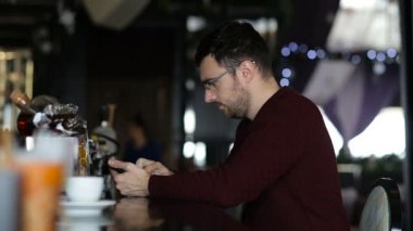 Genç bir adam barda otururken tablet kullanır